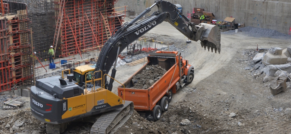 excavator filling dump truck on construction site