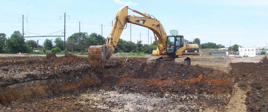 Track hoe digging out contaminated soil