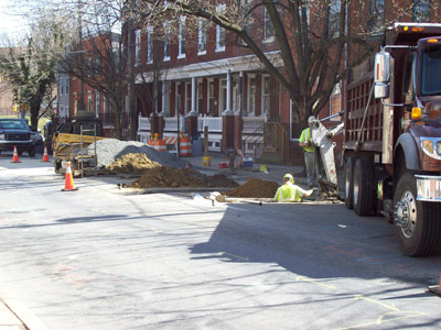 Workers in utility trenches cut in an urban street