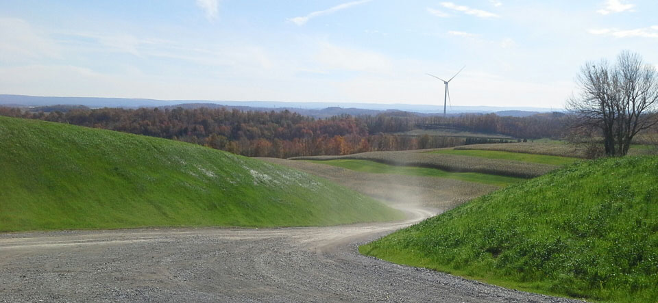 gravel road with wind turbine in background