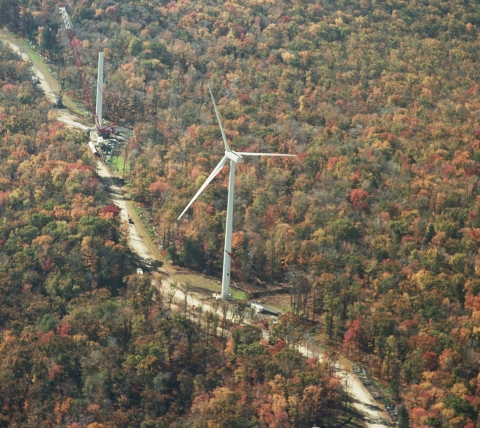 aerial of wind turbine installation in woods during fall