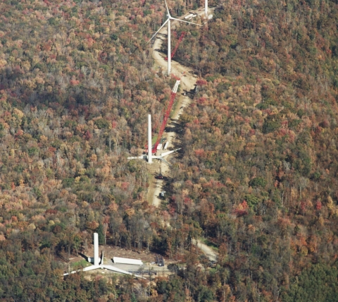 aerial of wind turbine installation in woods during fall