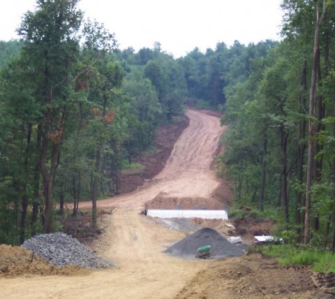 dirt road under construction surrounded by trees