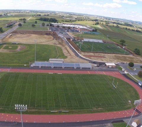 complete school football field and track with in progress ballfield in backgroud