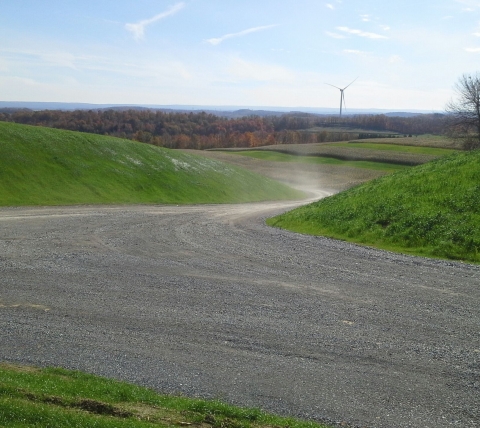 gravel road with wind turbine in background