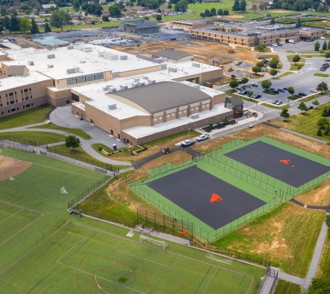 school campus an new tennis courts with in-progress school construction progress featuring foundation and utilities in background