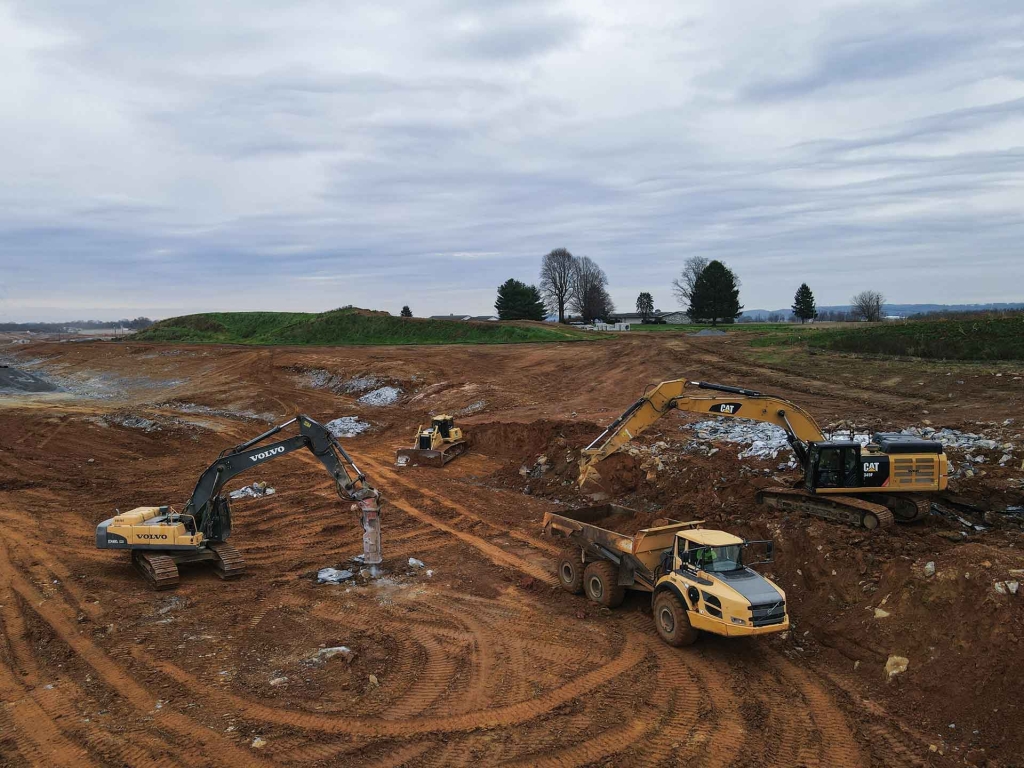 construction equipment grading and breaking rocks on site