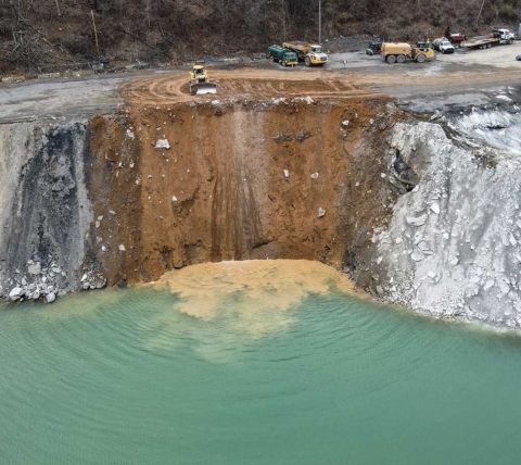 dozer dumping fill into quarry lake for quarry expansion excavation