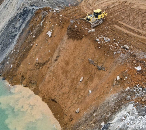 dozer dumping fill into quarry lake for quarry expansion excavation